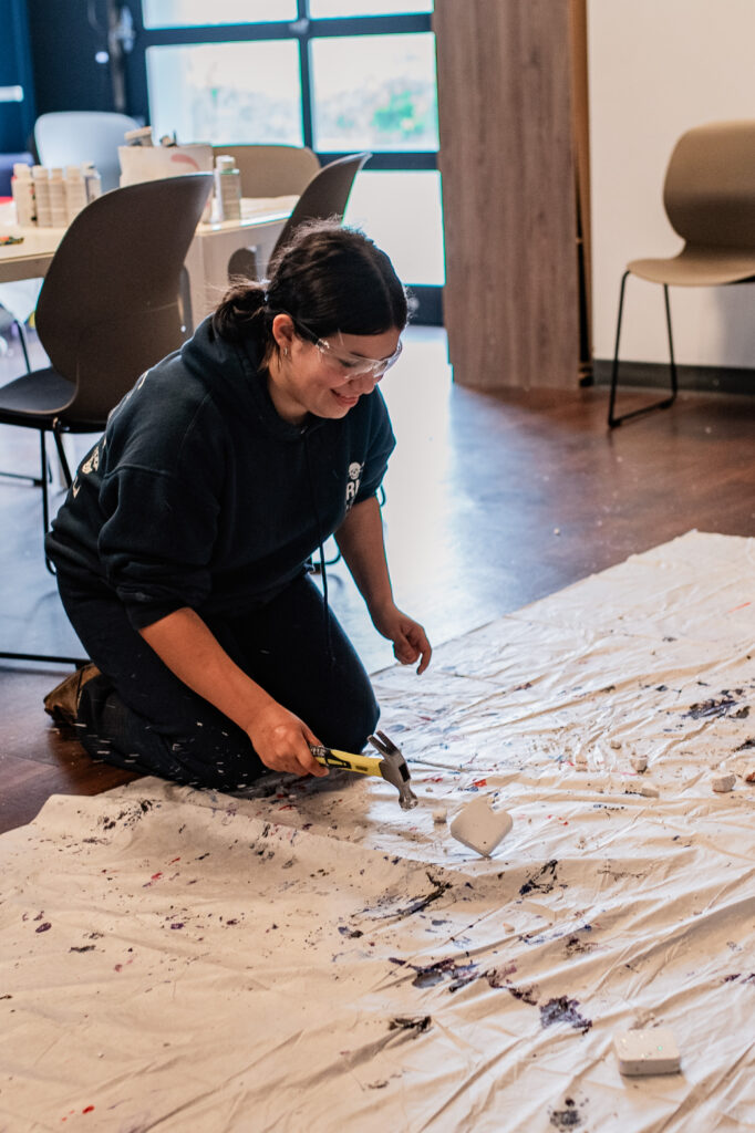 Participant at The Rage Workshop: Rage. Release. Rebirth. hitting a plaster brick with a hammer.